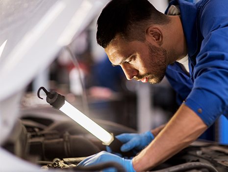 Mechanic inspecting hood of bus.