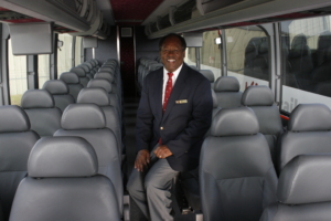 Driver sitting on a bus seat smiling.